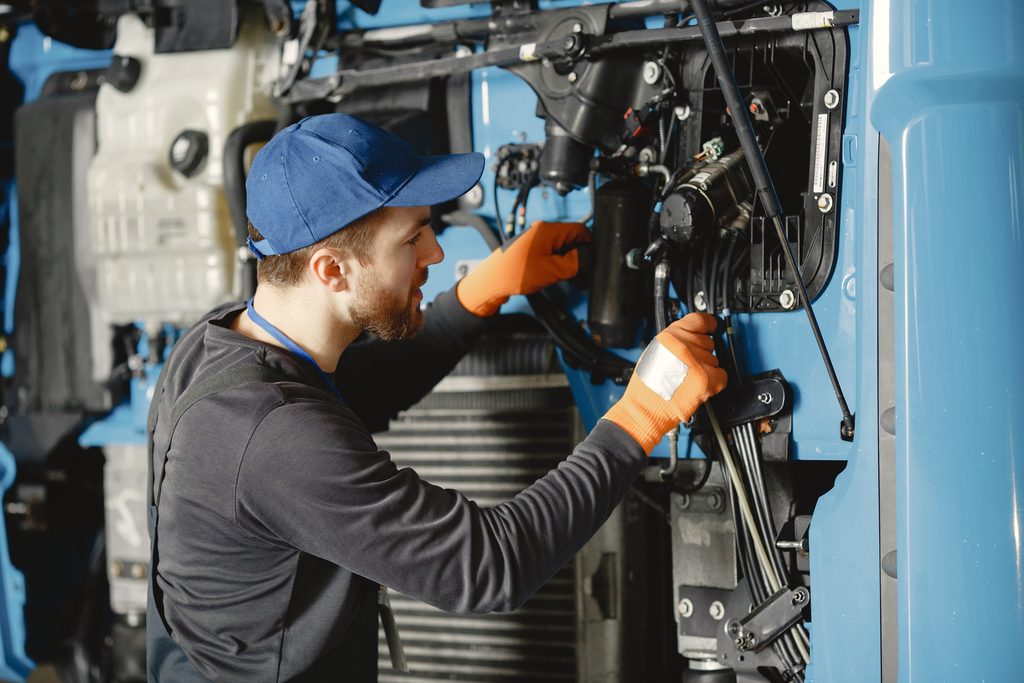 worker checks quality of truck in garage in uniform
